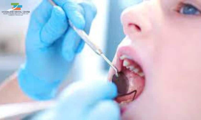 Young patient receiving dental examination with mirror tool during emergency dental care visit.