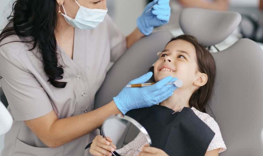 Pediatric dentist examining young girl's teeth during dental checkup in Puyallup.