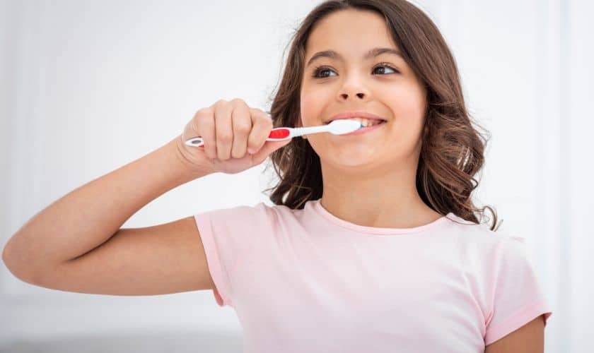 Young woman brushing her teeth with a red and white toothbrush.