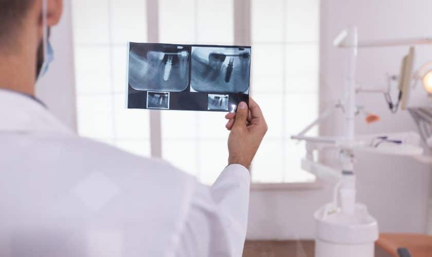 Dentist examining dental X-rays in a bright clinical office setting.