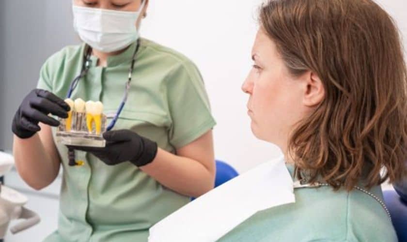 Dental assistant holding sample tooth shade guide during implant consultation with patient in Puyallup.