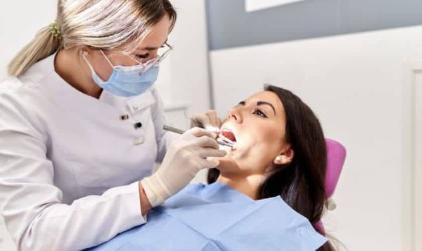 Dentist performing intraoral examination on patient in dental chair during sedation dentistry consultation.