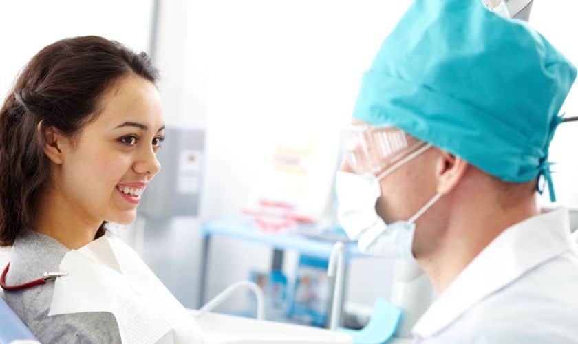 Smiling patient consulting with dentist in modern dental office treatment room.