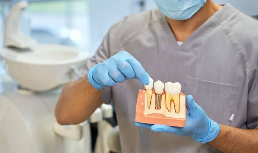 Dentist holding dental implant model showing tooth restoration options in Puyallup.
