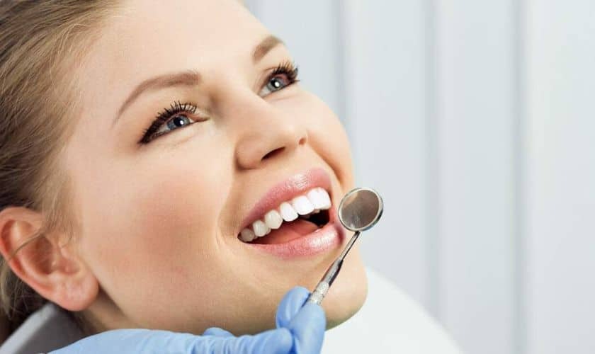 Woman displaying bright white teeth during dental examination with mirror in Puyallup.