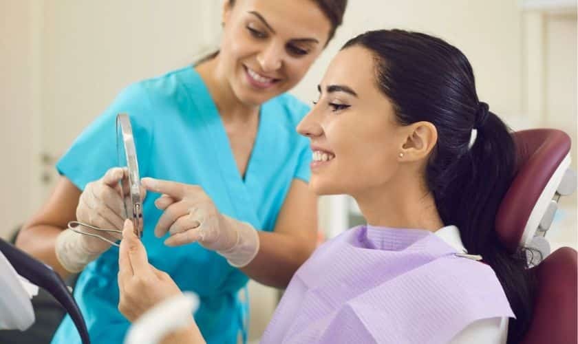 Dental hygienist showing patient mirror to review cosmetic smile results in Puyallup.
