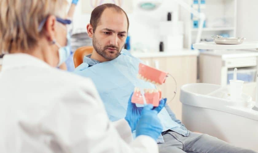Dentist showing dental implant models to male patient in Puyallup dental office.