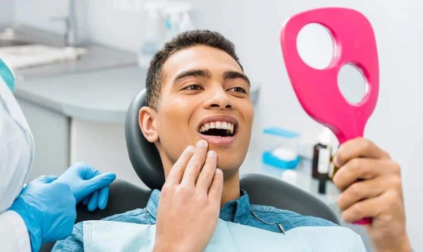 Happy patient examining his smile with mirror after cosmetic dental treatment in Puyallup.