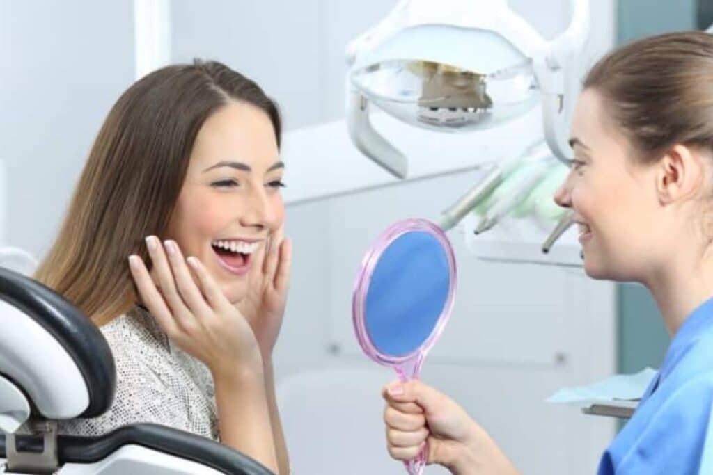 Patient admiring her smile in mirror after cosmetic dental treatment in Puyallup.