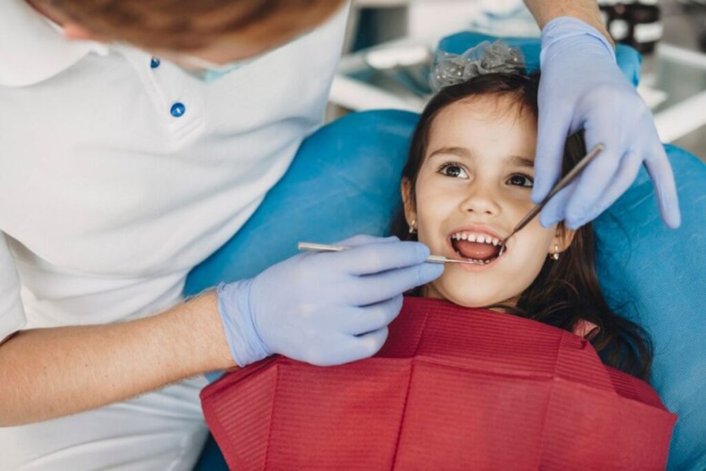 Young child smiling during pediatric dental examination with dentist in Puyallup.