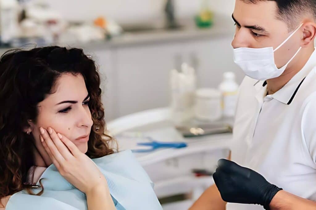 Woman experiencing tooth pain at dental office, consulting with masked dentist in Puyallup.