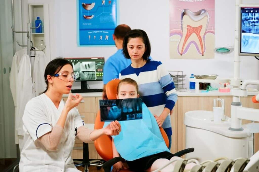 Pediatric dentist showing dental X-rays to young patient in Puyallup dental office.