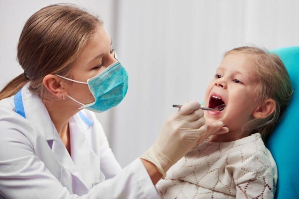 Pediatric dentist examining young child's teeth during dental checkup at Puyallup practice.