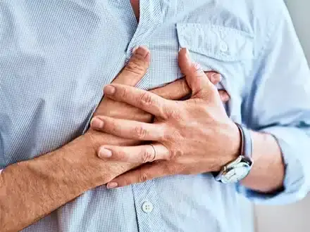 Man holding chest with both hands, experiencing chest pain or discomfort related to sleep apnea.