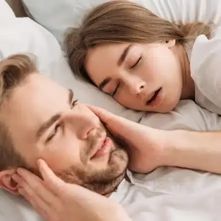 Couple sleeping peacefully together, illustrating snoring prevention benefits for restful sleep.