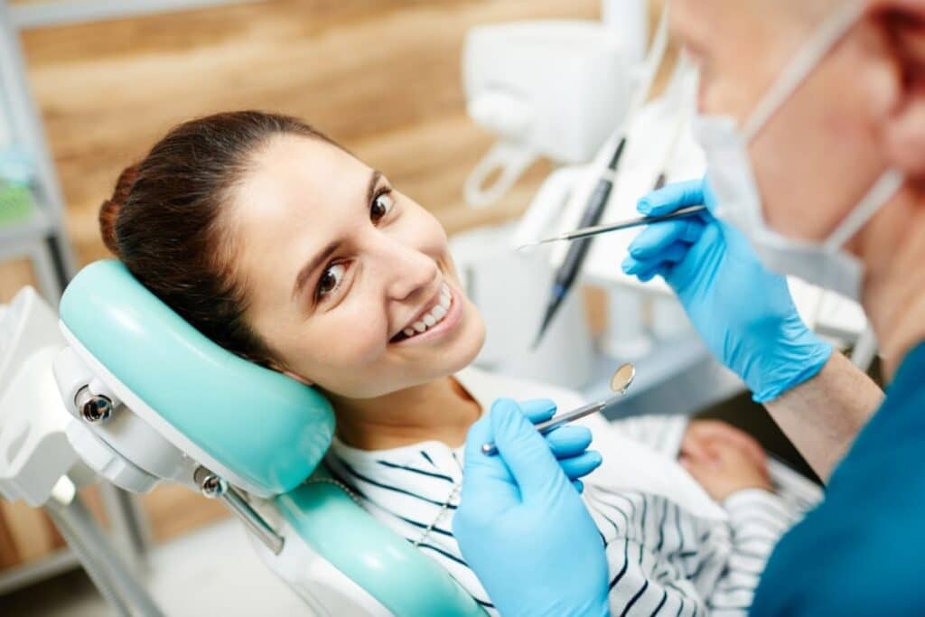Female patient smiling during cosmetic dental treatment with dentist holding instruments in Puyallup.