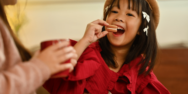 Young girl smiling while eating chocolate, demonstrating that treats can be part of good dental health.