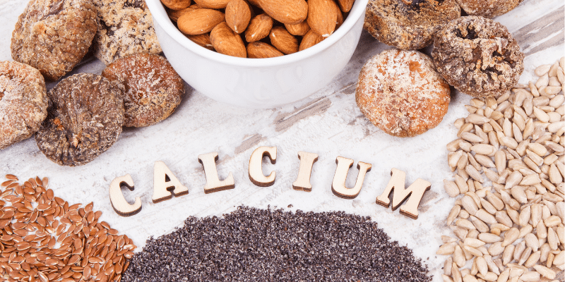 Calcium-rich foods including almonds, seeds, and legumes arranged with the word calcium for strong teeth and bones.