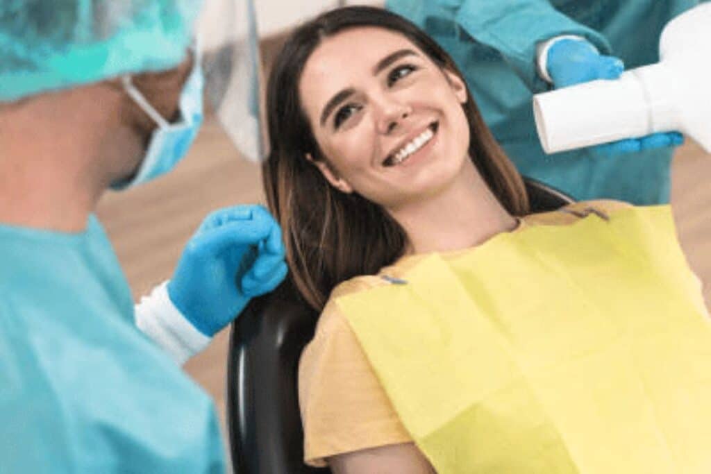 Smiling woman in yellow shirt receiving dental treatment from dentist in Puyallup.