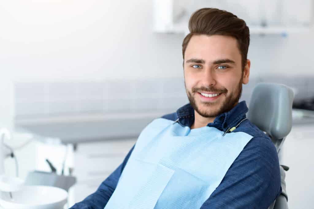 Smiling man in dental chair wearing protective bib at Puyallup dental practice.