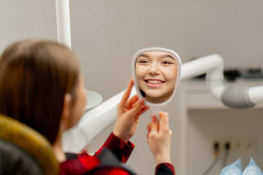Young patient smiling at mirror during cosmetic dental treatment in Puyallup.