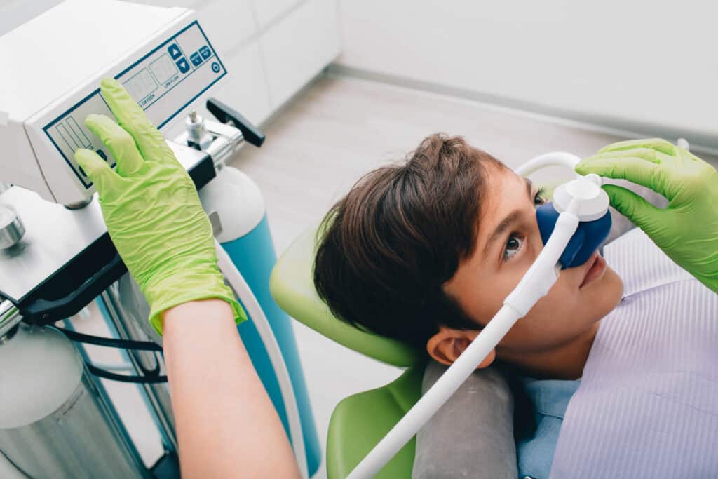 Young patient receiving dental treatment with protective eyewear in pediatric dental office.