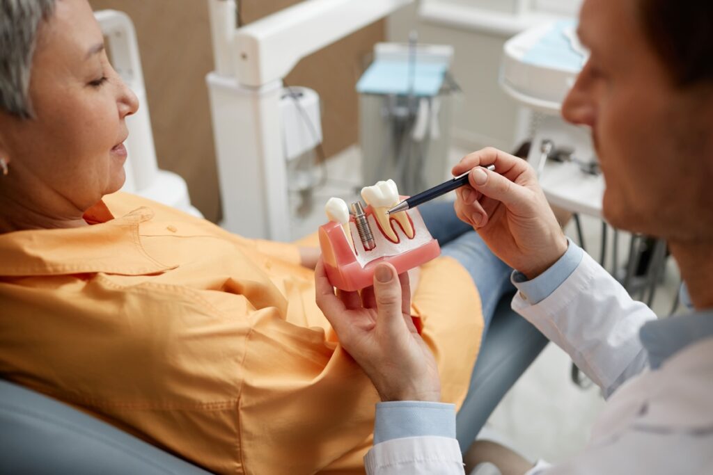 Dentist explaining dental implant model to patient during consultation in Puyallup office.