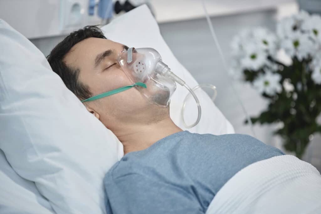 Patient wearing oxygen mask resting in dental chair after sedation dentistry treatment.