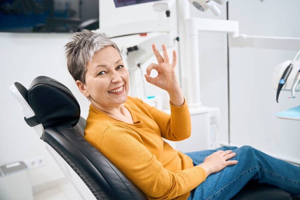 Satisfied patient giving OK sign in dental chair at Puyallup cosmetic dentistry office.