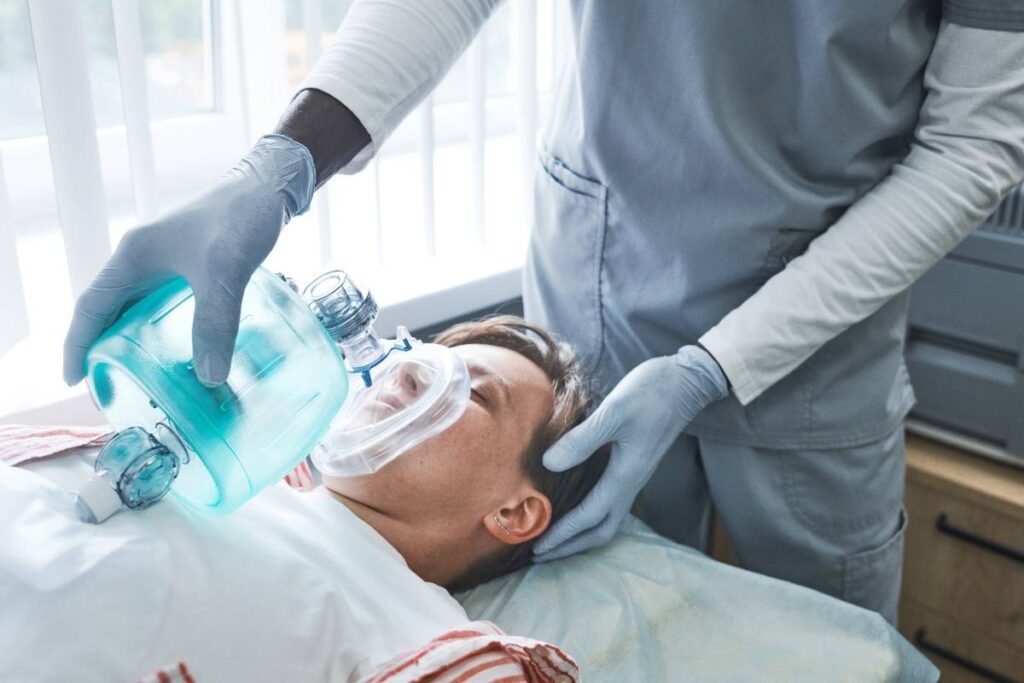 Pediatric dentist administering nitrous oxide sedation to child patient before dental treatment.