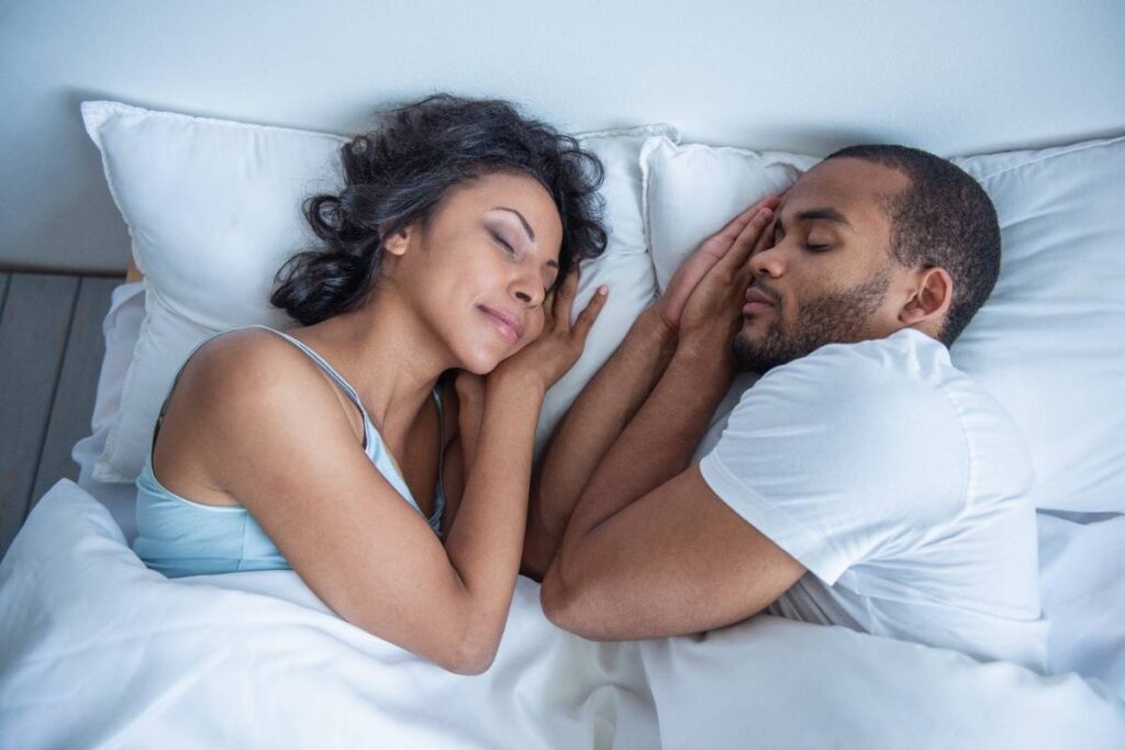 Couple sleeping peacefully in bed together, representing restful sleep important for dental implant patients with sleep apne.