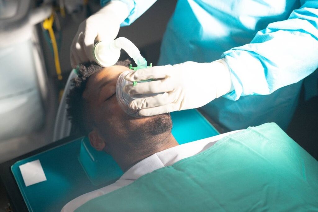 Dentist performing oral examination on patient during sedation dental treatment.