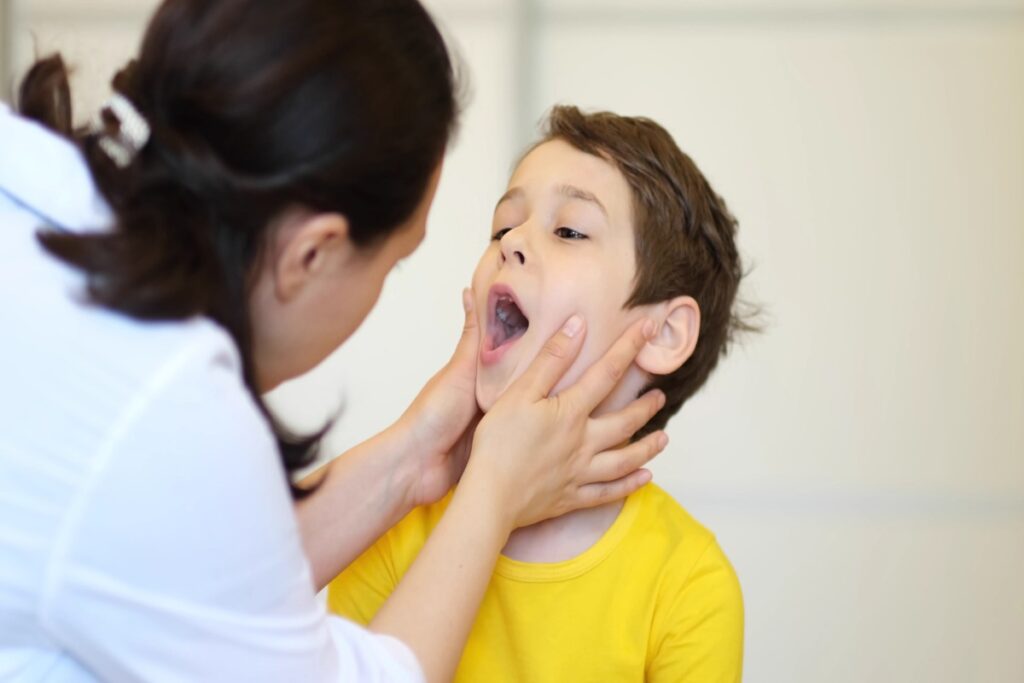 Dentist examining a child's open mouth to assess a chipped or broken tooth.
