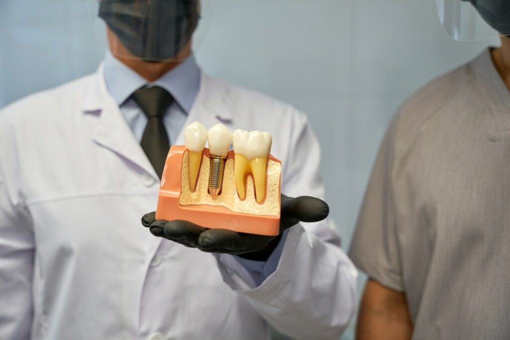 Dentist demonstrating dental implant model with crown and screw to patient in Puyallup.
